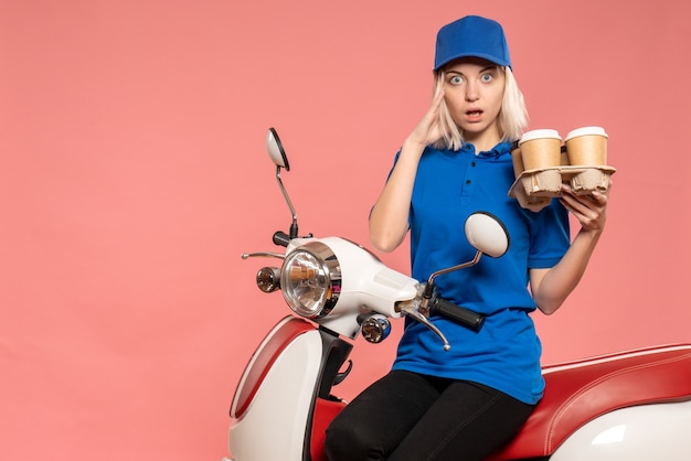 Vue de face femme courrier sur vélo avec tasses à café sur le rose