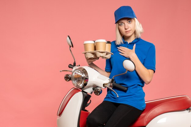 Vue de face femme courrier sur vélo avec tasses à café sur le rose