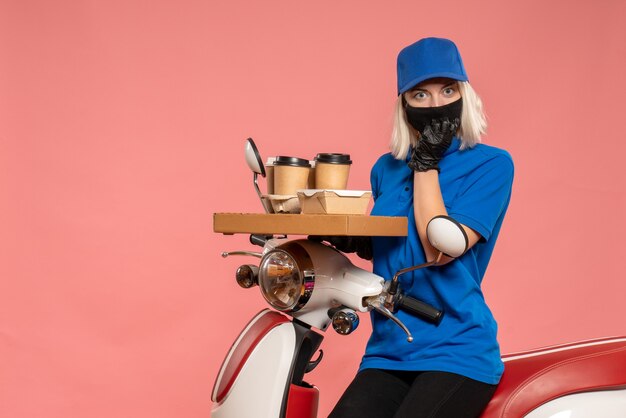 Vue de face femme courrier sur vélo avec tasses à café sur le rose