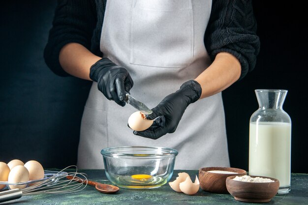 Vue de face femme cuisinier casser des œufs pour la pâte sur la pâtisserie foncée gâteau boulanger ouvrier cuisine hotcake emploi