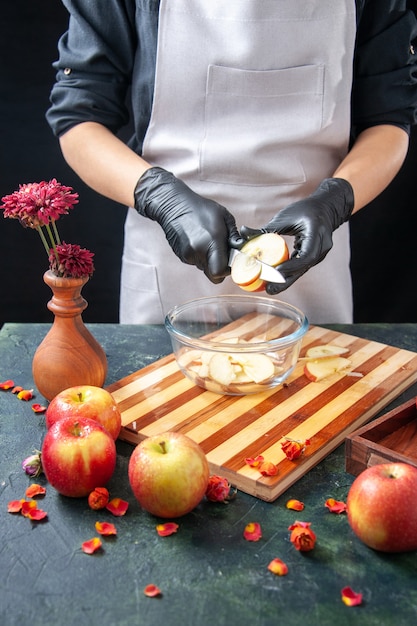 Vue de face femme cuisinier coupe des pommes dans une assiette sur un régime de fruits noirs salade alimentaire repas jus exotique travail tarte gâteau