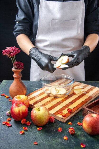Vue de face femme cuisinier coupe des pommes dans une assiette sur un régime de fruits noirs salade alimentaire repas jus exotique travail tarte gâteau