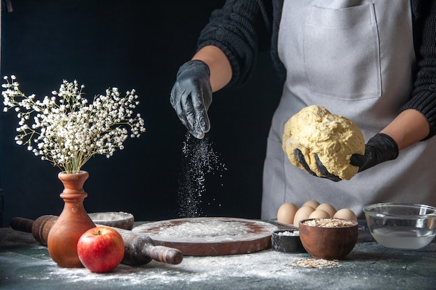 Vue de face femme cuisinier étaler la pâte sur un travail sombre four à tarte cru pâtisserie hotcake boulangerie oeuf