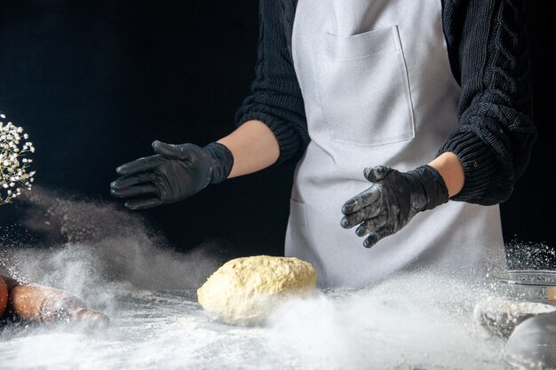 Vue de face femme cuisinier jetant de la pâte dans la farine blanche sur pâte foncée travail d'oeuf boulangerie hotcake pâtisserie cuisine cuisine