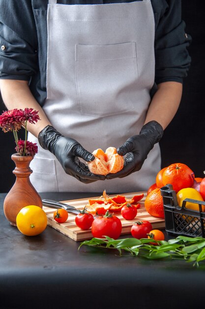 Vue de face femme cuisinier nettoyage mandarines sur sombre cuisson salade santé régime légumes repas nourriture fruit travail