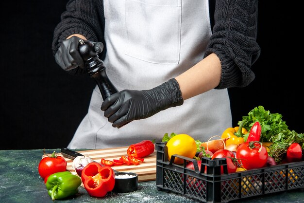 Vue de face femme cuisinier piquant des légumes sur un repas de cuisine de cuisine de salade de couleur sombre