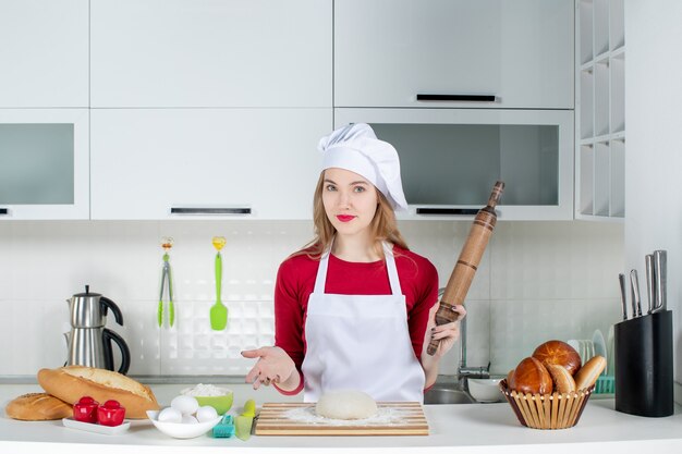 Vue de face femme cuisinier tenant un rouleau à pâtisserie dans la cuisine