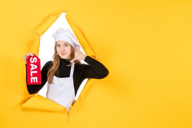 Vue de face femme cuisinier tenant vente rouge écrit sur la couleur jaune travail cuisine cuisine émotion photo alimentaire