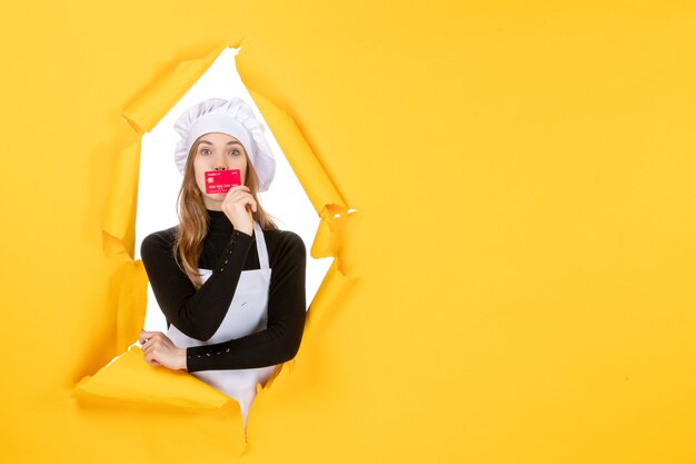 Vue de face femme cuisinière tenant une carte bancaire rouge sur argent jaune couleur travail photo nourriture cuisine émotion