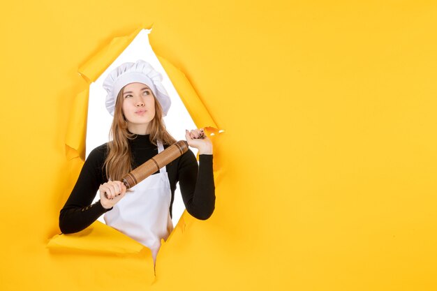 Vue de face femme cuisinière tenant un rouleau à pâtisserie et pensant au travail de cuisine jaune couleur cuisine nourriture soleil photo