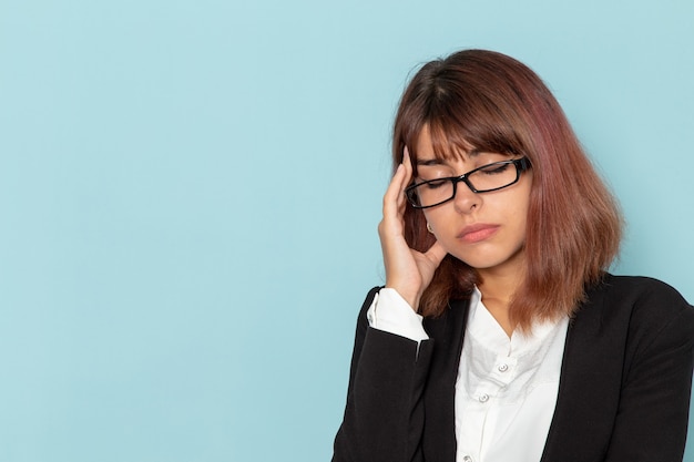 Vue de face femme employé de bureau en costume strict ayant des maux de tête sur la surface bleue