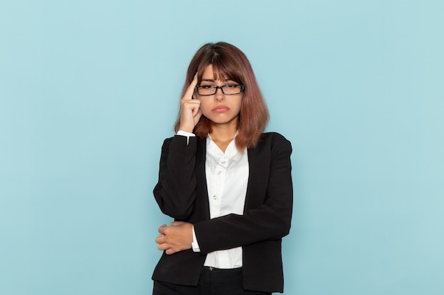 Vue de face femme employé de bureau en costume strict pensant stressant sur la surface bleue