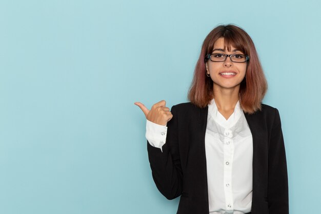 Vue de face femme employé de bureau posant et souriant sur la surface bleue