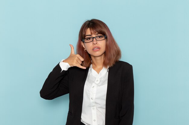 Vue de face femme employé de bureau posant sur une surface bleu clair