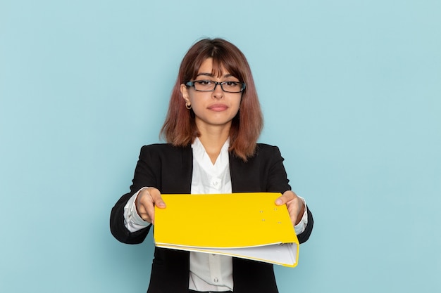 Vue de face femme employé de bureau tenant un fichier jaune sur la surface bleue