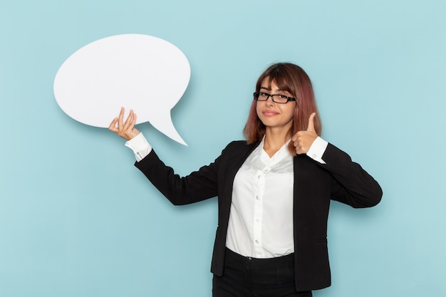 Vue de face femme employé de bureau tenant une pancarte blanche sur la surface bleue