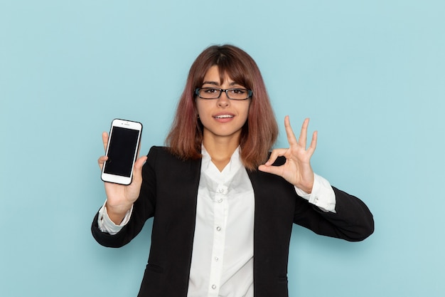 Vue de face femme employé de bureau tenant le téléphone sur la surface bleue