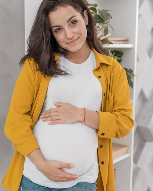 Vue de face de la femme enceinte tenant son ventre à la maison