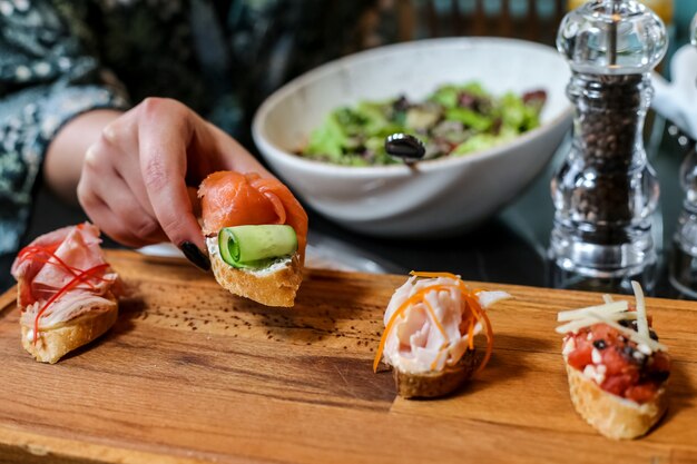 Vue de face une femme est un mélange de bruschettas sur un stand