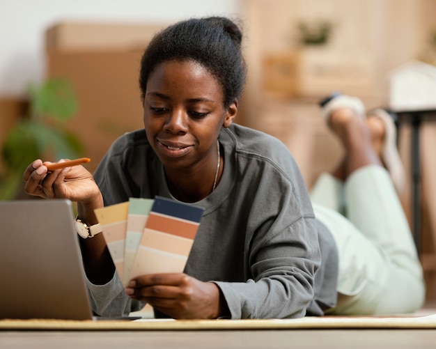 Vue de face de la femme faisant des plans pour redécorer la maison avec un ordinateur portable et une palette de couleurs