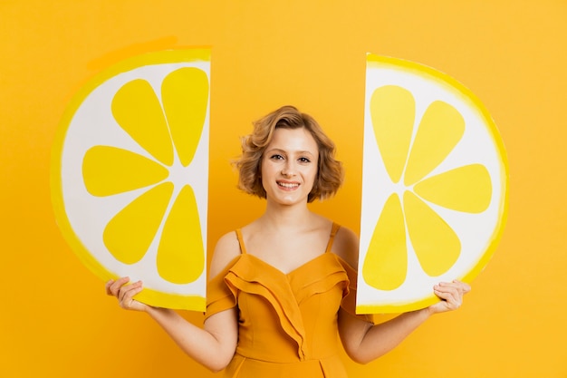 Photo gratuite vue de face de femme heureuse posant avec des décorations de tranches de citron