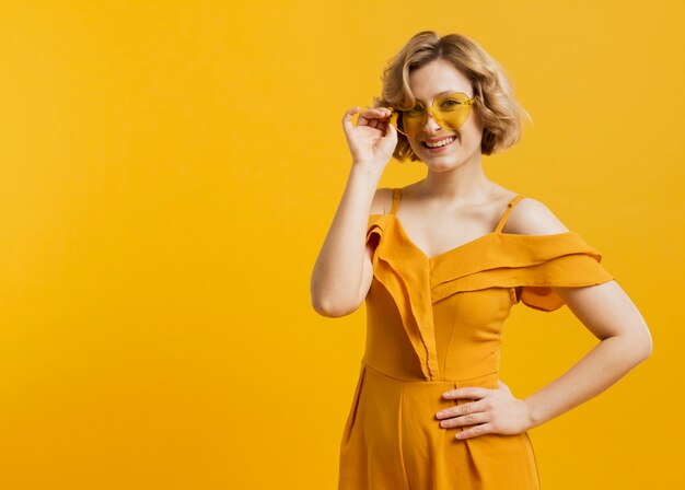 Vue de face de femme heureuse posant tout en portant des lunettes de soleil