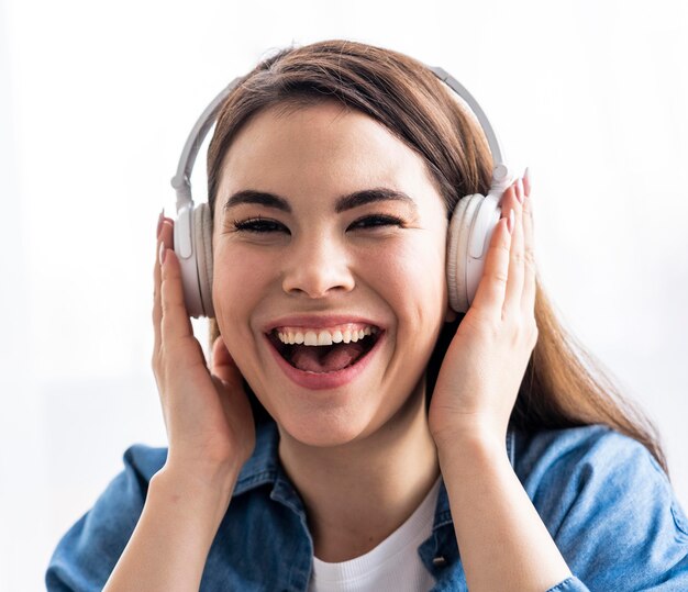 Vue de face d'une femme heureuse en riant et en écoutant de la musique sur des écouteurs