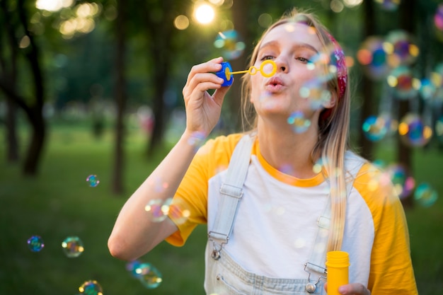 Vue de face de la femme jouant à l'extérieur avec des bulles