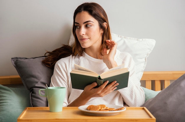 Vue de face de la femme lisant et prenant son petit déjeuner à la maison