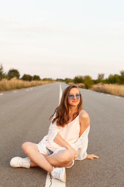 Vue de face de la femme avec des lunettes de soleil posant sur la route