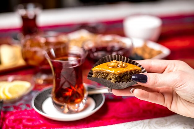 Vue de face femme mangeant un baklava azerbaïdjanais traditionnel avec du thé