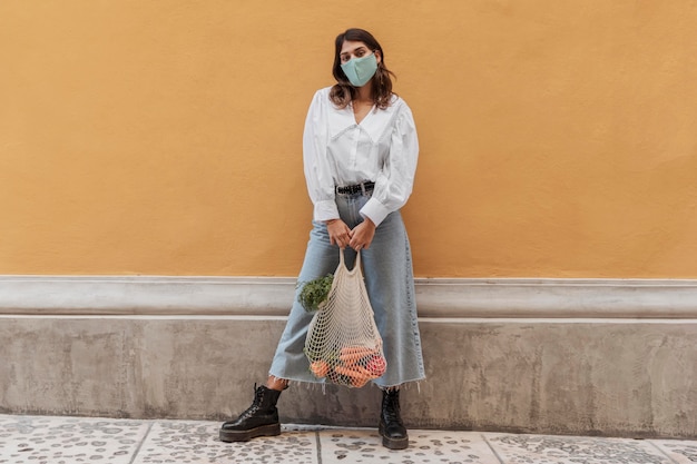 Photo gratuite vue de face de la femme avec masque facial et sacs d'épicerie à l'extérieur