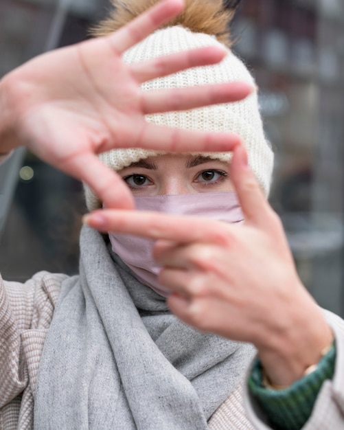 Photo gratuite vue de face de la femme avec un masque médical faisant le cadre avec les mains