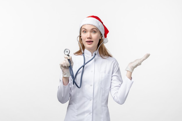 Vue de face d'une femme médecin à l'aide d'un stéthoscope sur un mur blanc