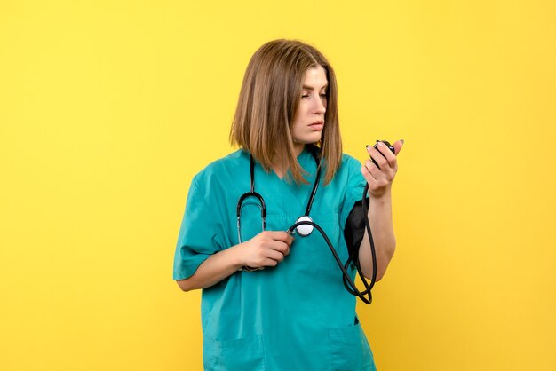 Vue de face femme médecin à l'aide de tonomètre sur l'espace jaune