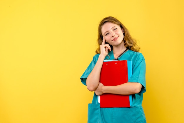 Vue de face de la femme médecin avec analyses sur mur jaune