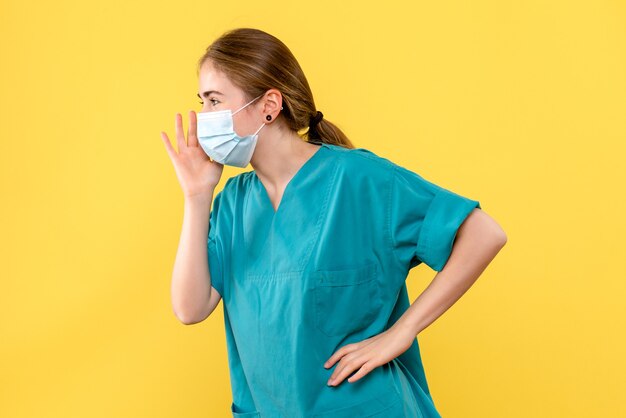 Vue de face femme médecin appelant sur fond jaune virus de la santé pandémique covid