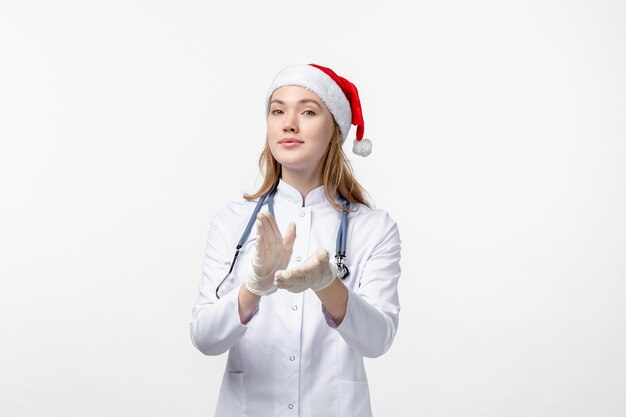 Vue de face d'une femme médecin applaudissant sur un mur blanc