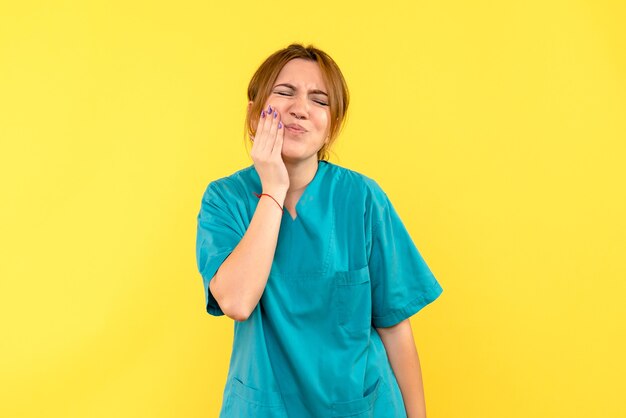 Vue de face femme médecin ayant mal aux dents sur l'espace jaune