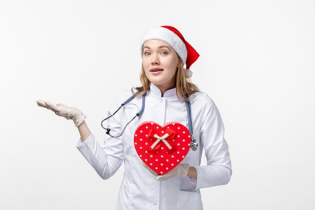 Vue de face d'une femme médecin avec un cadeau de vacances sur un mur blanc