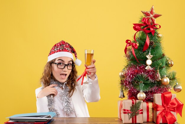 Vue de face femme médecin célébrant Noël avec verre de champagne