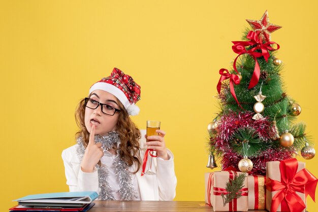 Vue de face femme médecin célébrant Noël avec verre de champagne