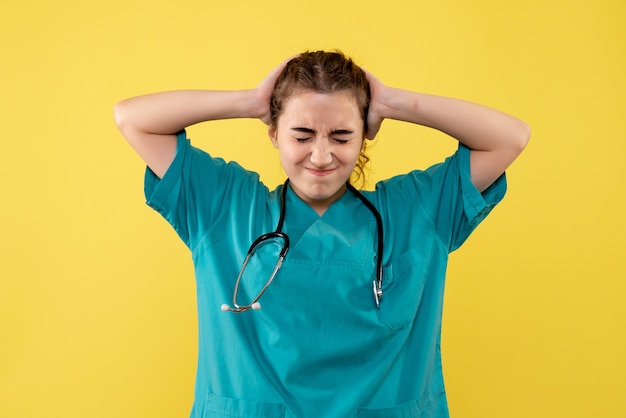 Vue de face femme médecin en chemise médicale ayant des maux de tête, couleur virus covid-19 émotion de santé uniforme