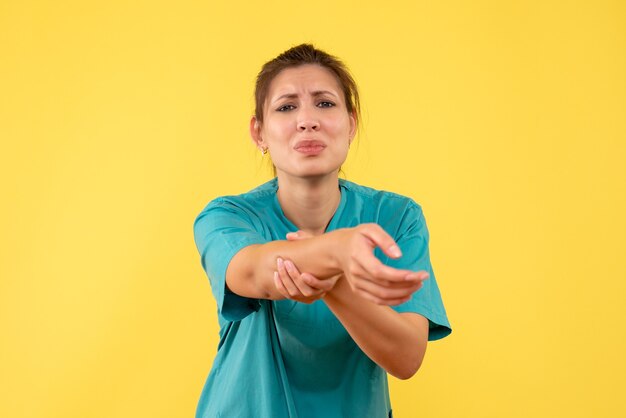 Vue de face femme médecin en chemise médicale blessé sa main sur fond jaune