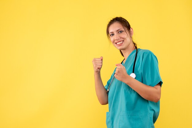 Vue de face femme médecin en chemise médicale en boxe stand sur fond jaune