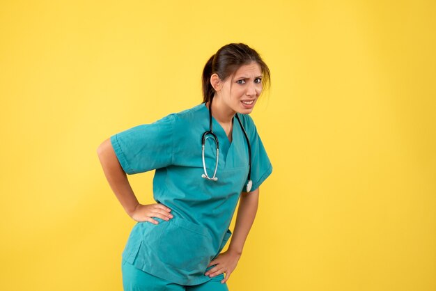 Vue de face femme médecin en chemise médicale sur fond jaune