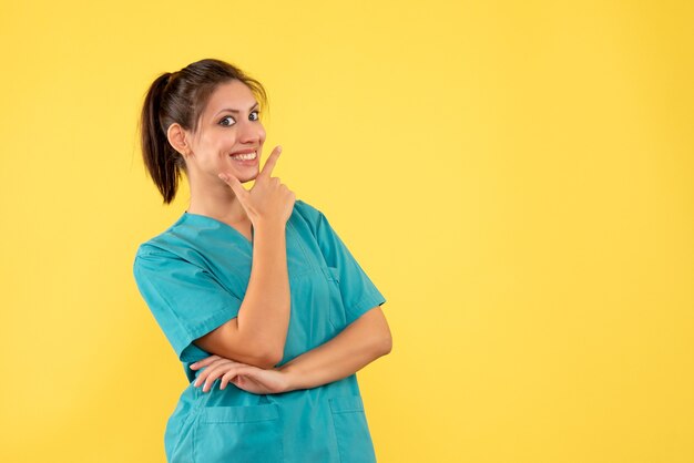 Vue de face femme médecin en chemise médicale sur fond jaune