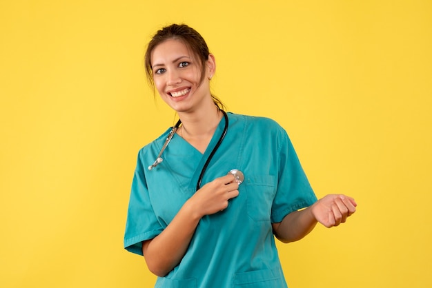 Vue de face femme médecin en chemise médicale sur fond jaune