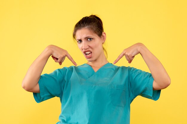 Vue de face femme médecin en chemise médicale sur fond jaune