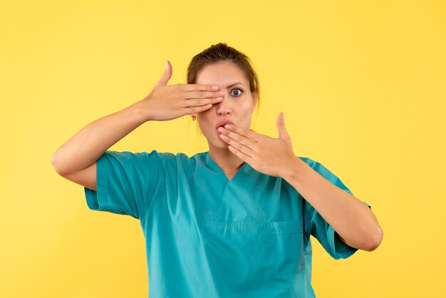 Vue de face femme médecin en chemise médicale sur fond jaune